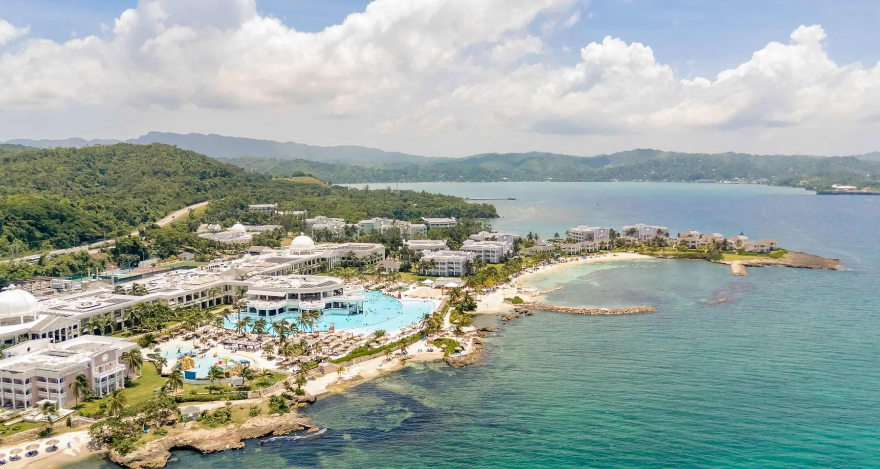 Aerial view of the Grand Palladium resort: white buildings, a lagoon pool and beaches on a green peninsula